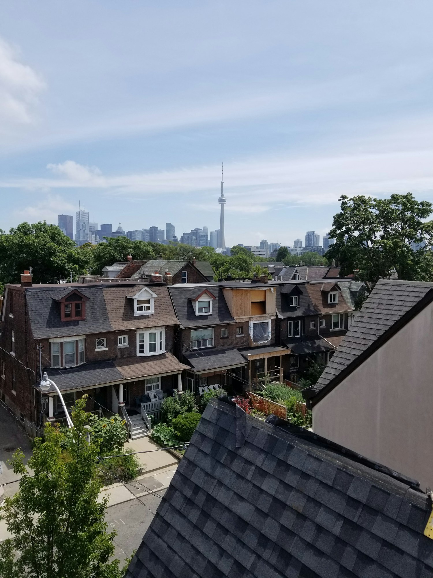 Toronto neighbourhood rooftops with the CN Tower and downtown skyline beyond